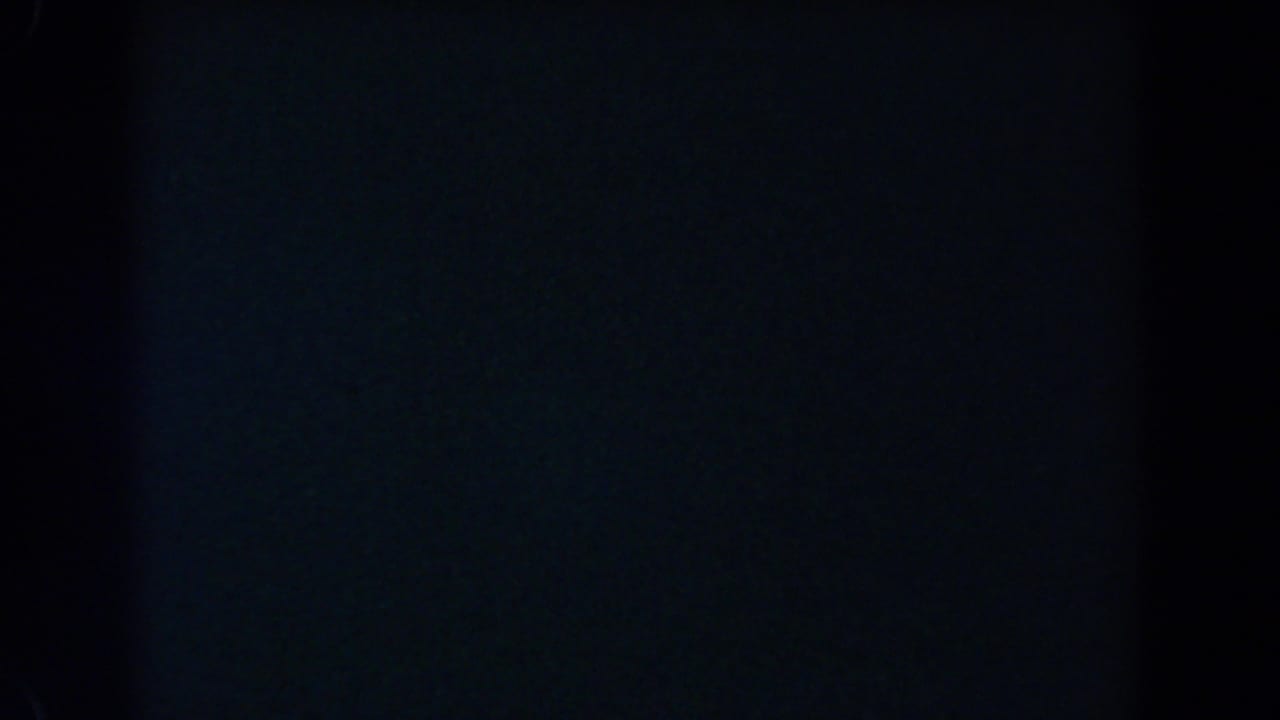 Nearly black 8mm frame with faint blue tone and film grain.