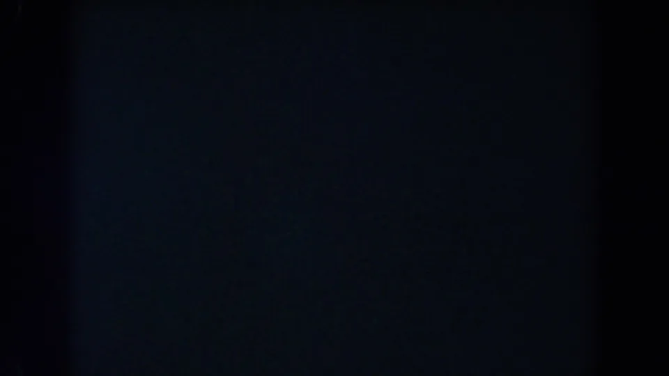 Underexposed 8mm frame with a central vertical dark band and faint blue-black areas, based on the 1962 Glendale clip metadata.
