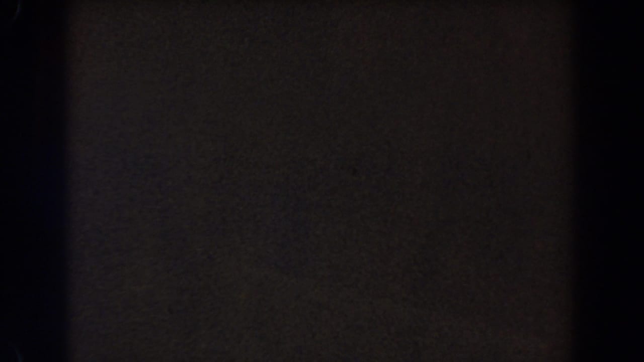 Dim 8mm frame from the 1962 Glendale home movie, showing a dark divider and muted brown-gray exposure with grain.