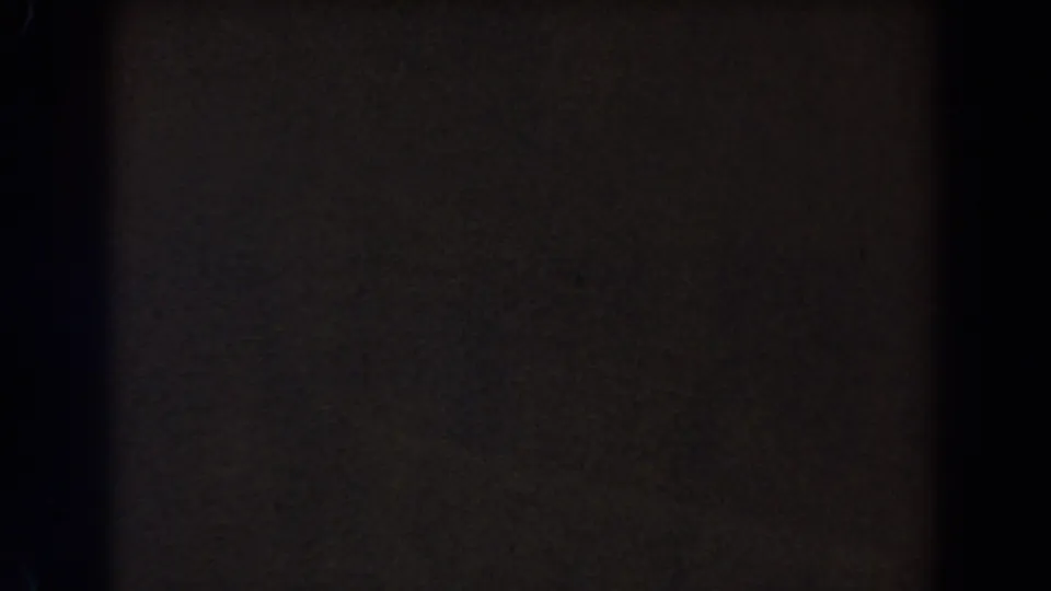 Dim 8mm frame from the 1962 Glendale home movie, showing a dark divider and muted brown-gray exposure with grain.