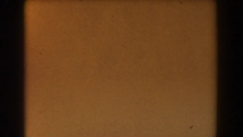 Amber-toned 8mm frame from the 1962 Glendale clip, with dark borders, grain, and small specks visible.