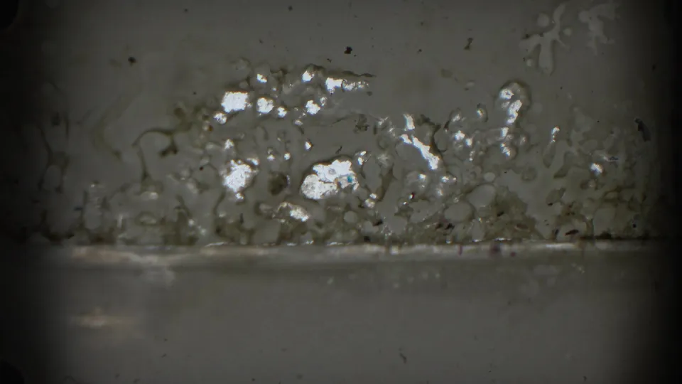 1962 Glendale 8mm frame showing gray film texture with dust, scratches, and a bright mottled surface mark near the bottom left.