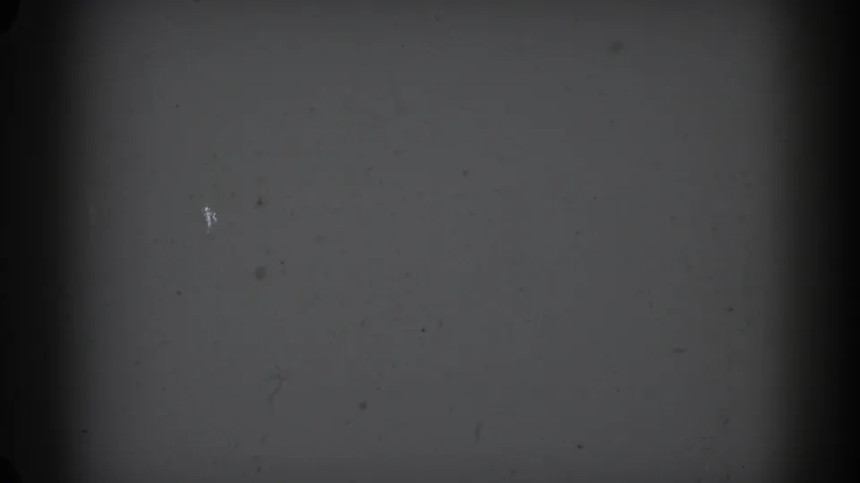 1962 Glendale 8mm frame showing blank gray film texture with dark edge vignetting, scattered dust, and scratch marks.