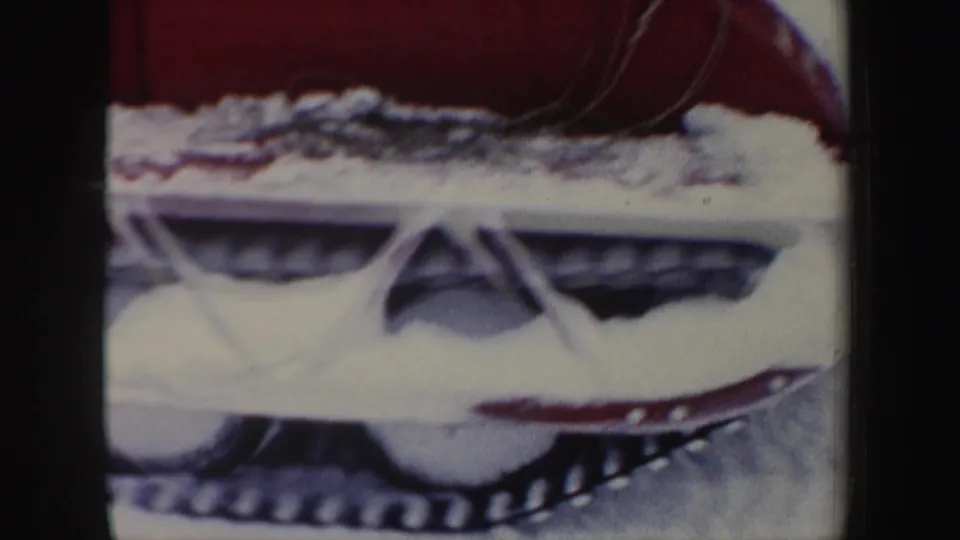 Close 1962 home-movie view of the snowmobile's lower frame, showing snow around the track and ski assembly.