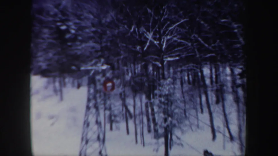 1962 New Hampshire 8mm frame showing snowy trees and a small red cable car partly visible in the winter landscape.