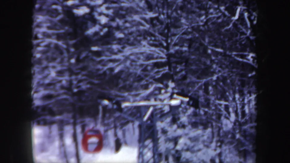1962 New Hampshire 8mm frame with the red cable car near the lower left, surrounded by snowy woods and visible cable hardware.