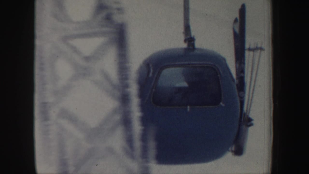 Blue ski lift chair passing near a metal tower in snowy conditions.