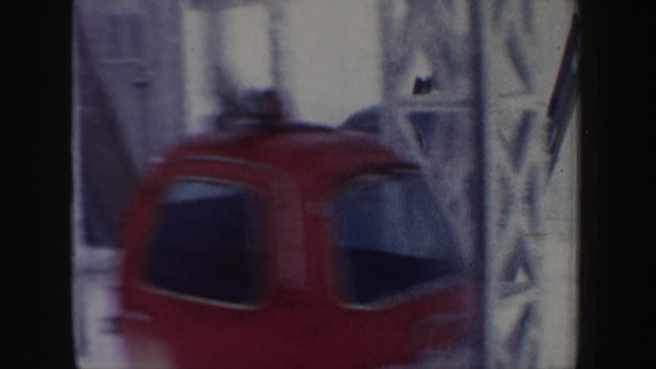 Red ski lift chair moving past a tower with snowy background.