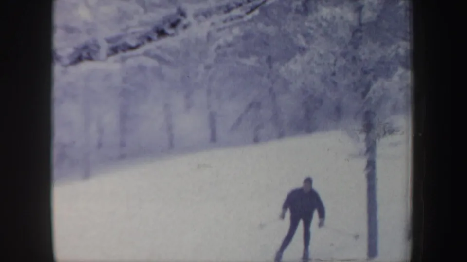 A distant skier moves across a snow-covered slope in the 1962 New Hampshire home-movie ski footage.