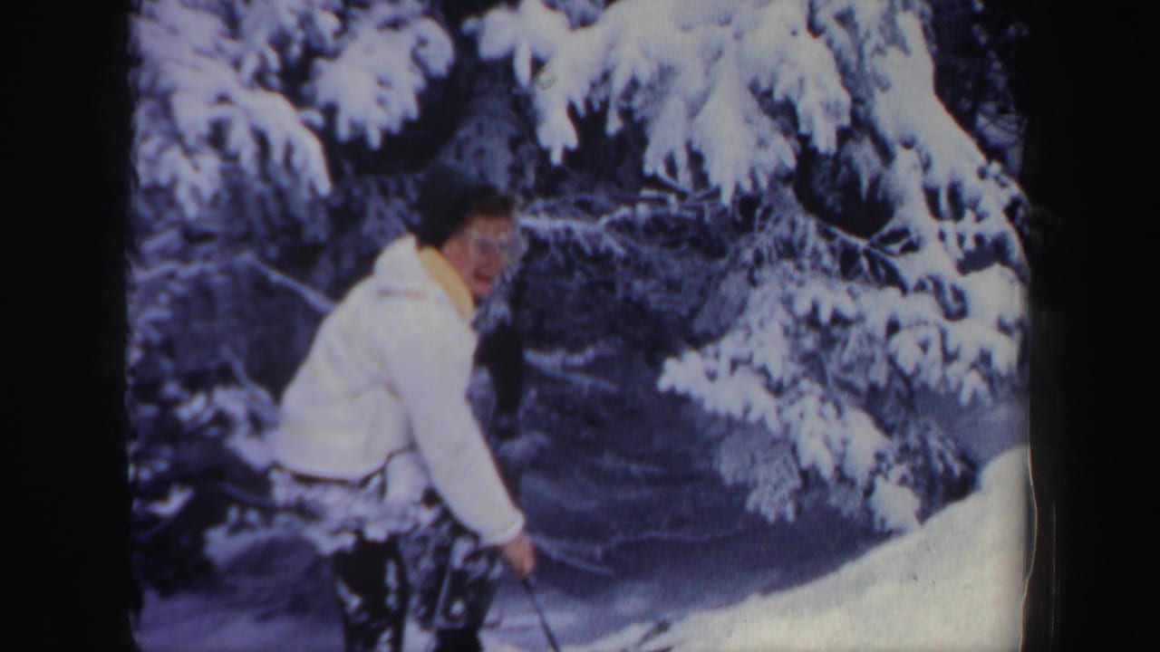 Woman with a ski pole looks back while standing on a snowy slope.