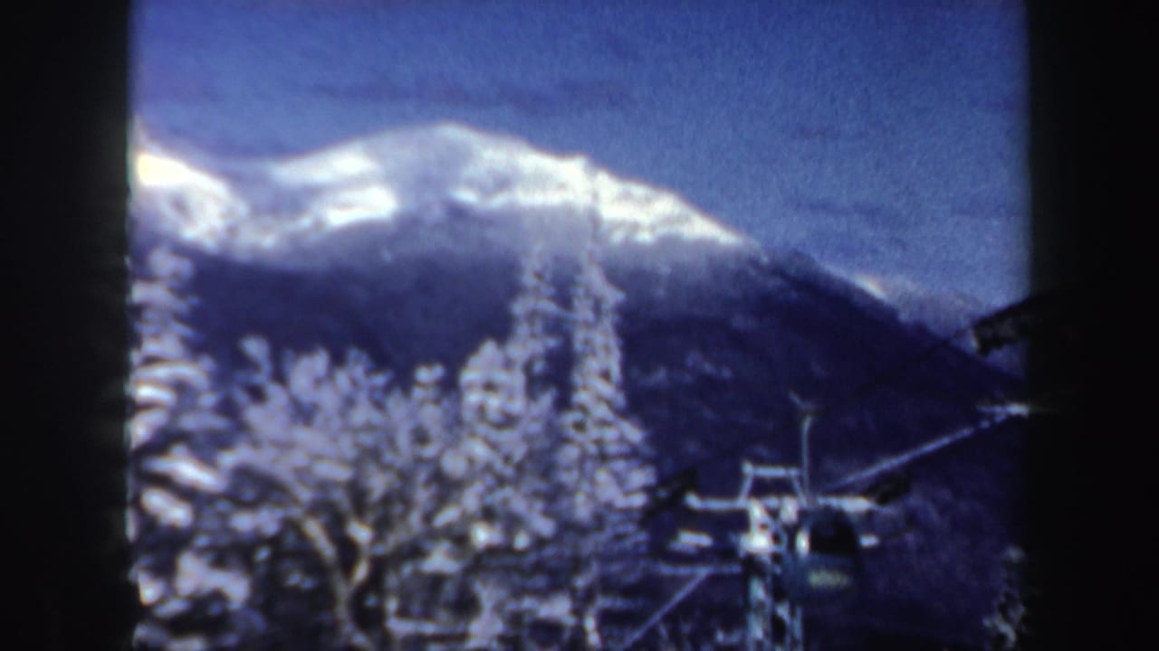 1962 New Hampshire 8mm frame showing snow-covered trees, a ski lift gondola, and a distant mountain ridge.