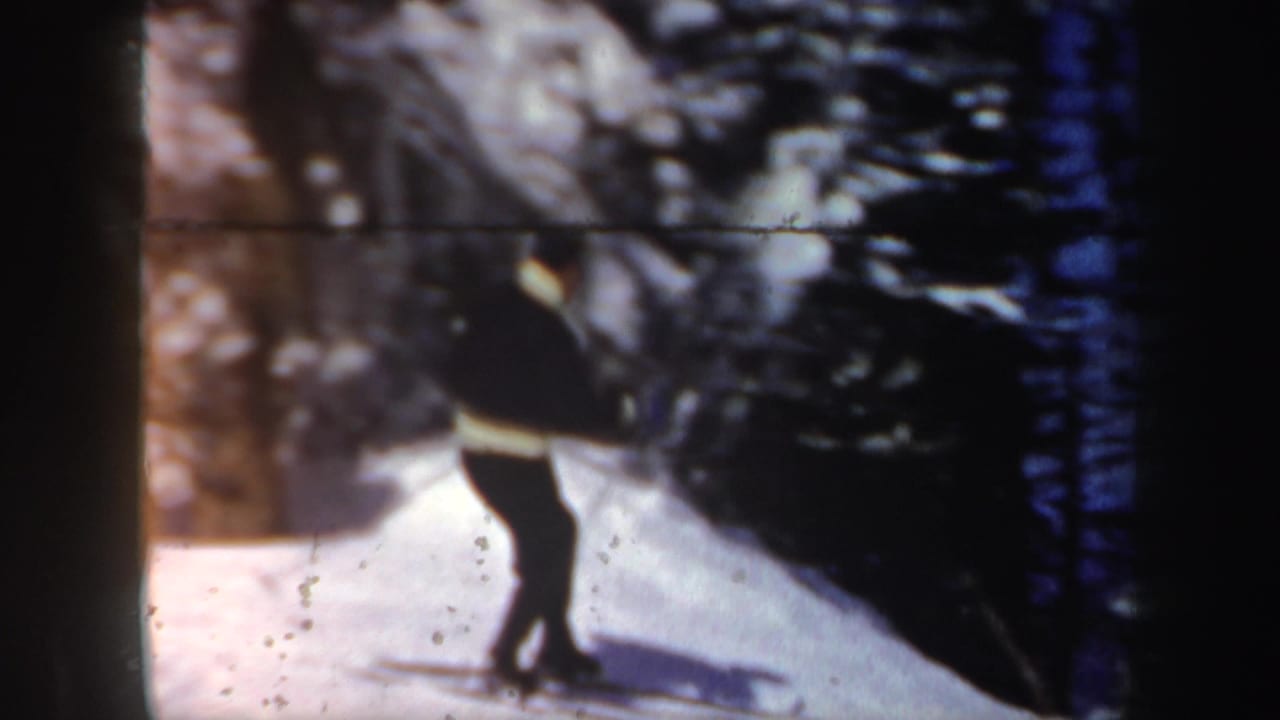 A lone skier in a dark jacket with a light band moves across a snowy New Hampshire slope in 1962 home-movie footage.