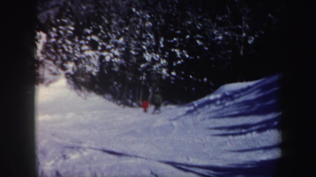 Two distant men near the evergreen edge of a snowy New Hampshire slope, filmed on 8mm in 1962.