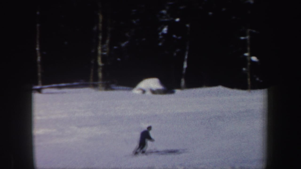 1962 New Hampshire 8mm frame showing the skier lower on the hill, with snow-covered ground and dark forest in the background.