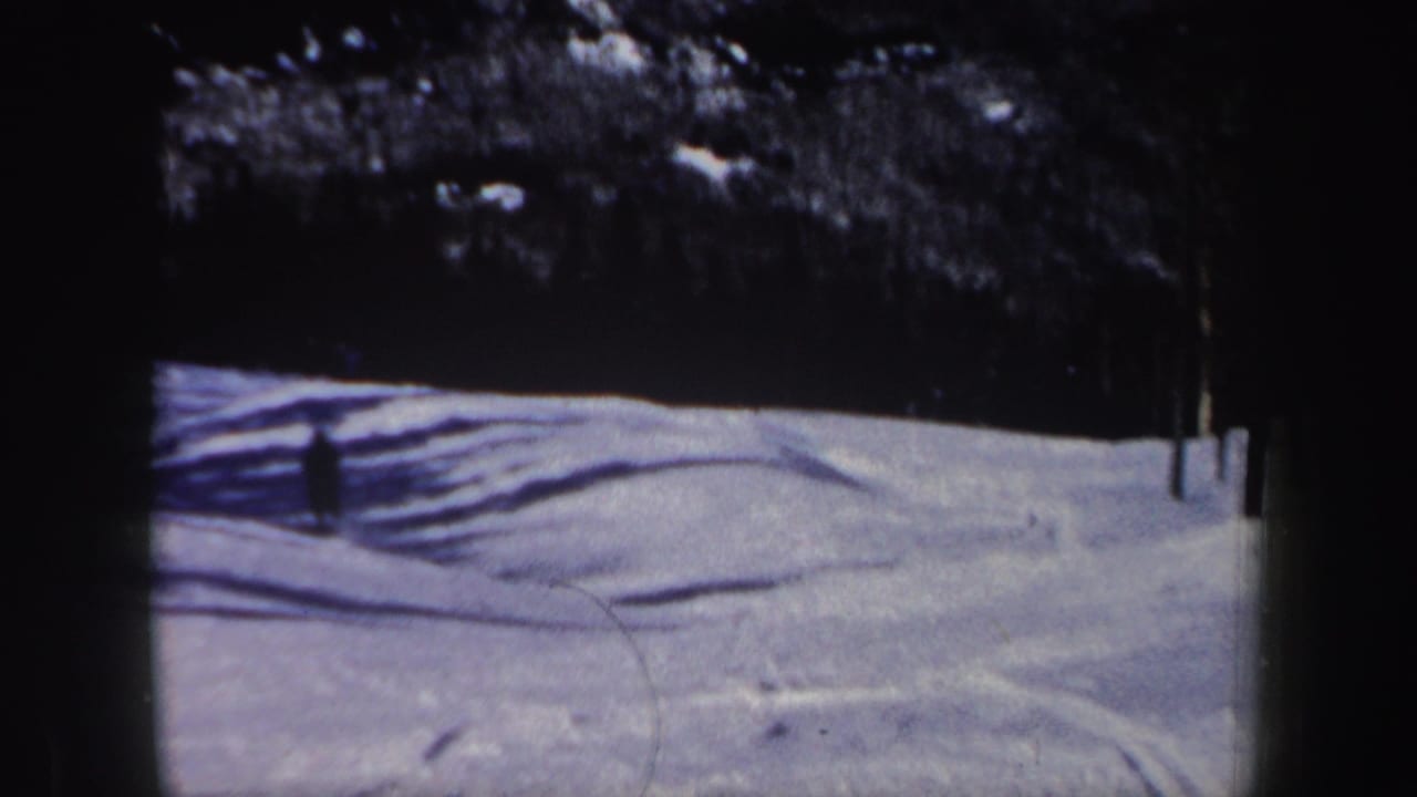 1962 New Hampshire 8mm frame with the skier farther across the slope, leaving a wide view of snow, tracks, shadows, and trees.