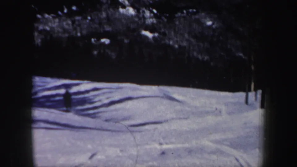 1962 New Hampshire 8mm frame with the skier farther across the slope, leaving a wide view of snow, tracks, shadows, and trees.