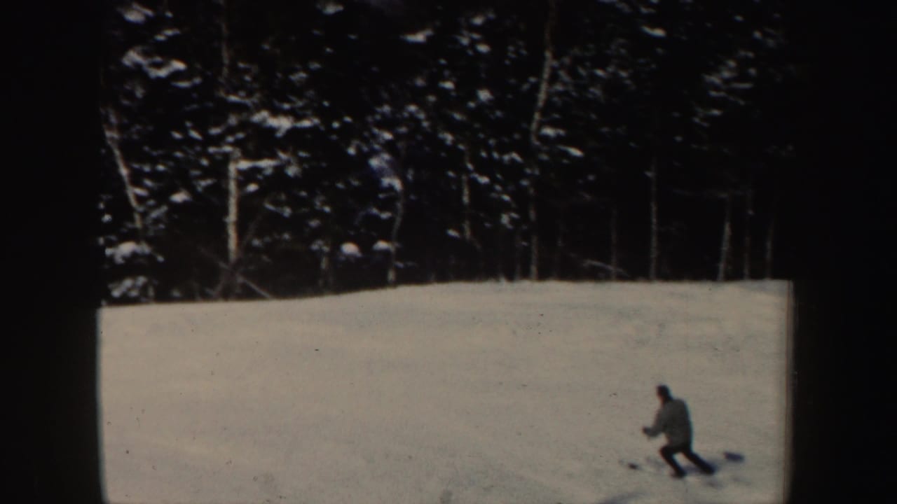 Distant skier on a New Hampshire snow slope in 1962, with dark evergreen trees lining the background.
