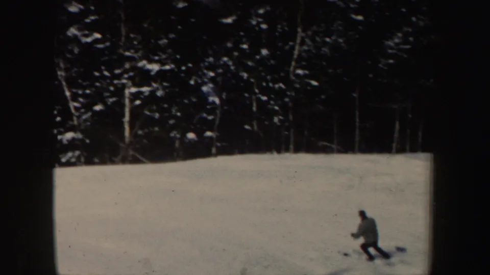 Distant skier on a New Hampshire snow slope in 1962, with dark evergreen trees lining the background.