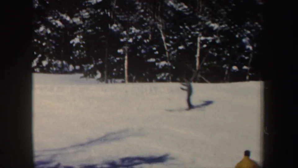1962 New Hampshire ski footage frame with a partly visible skier entering the lower right of a sunlit snowfield.