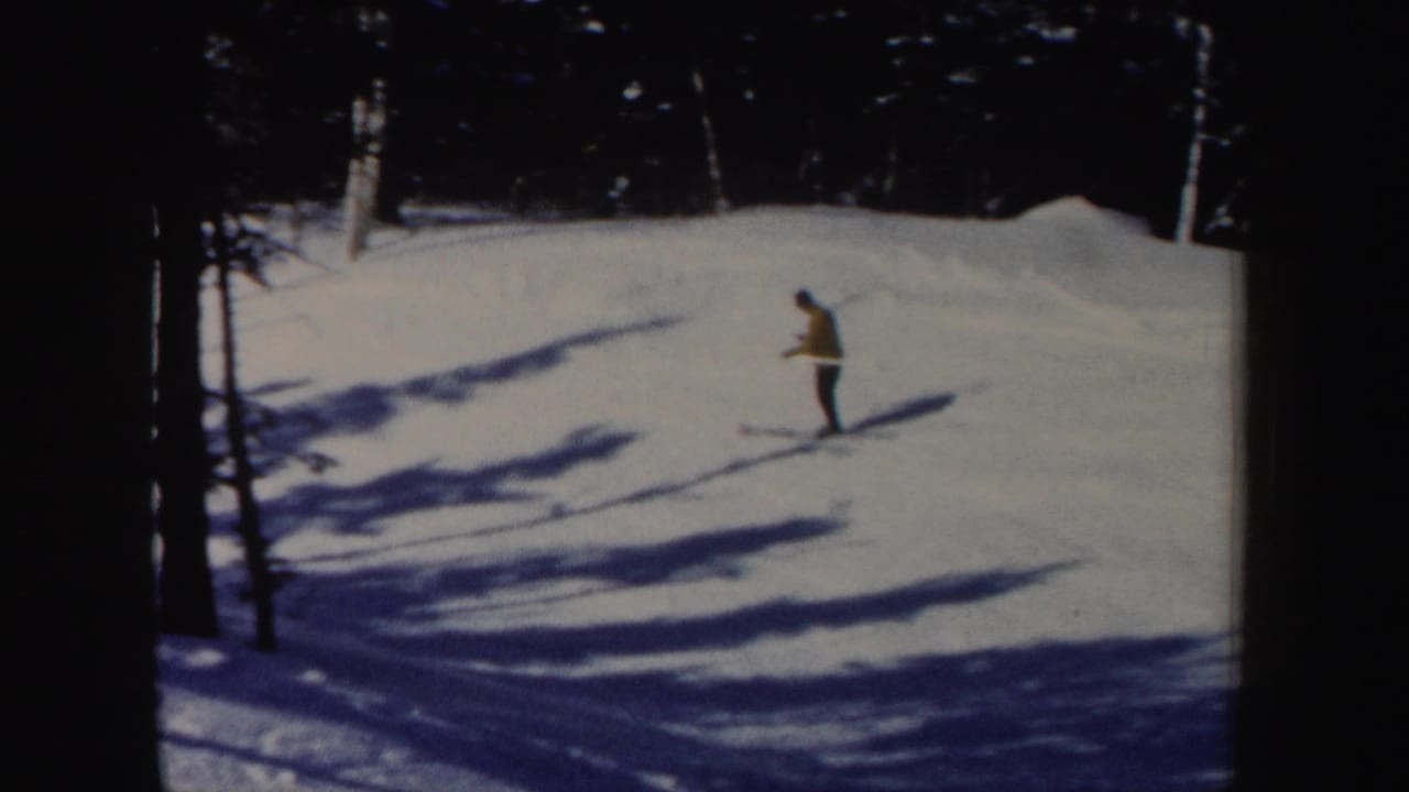 1962 New Hampshire 8mm frame with a yellow-jacket skier moving across a snowy incline under tree shadows.