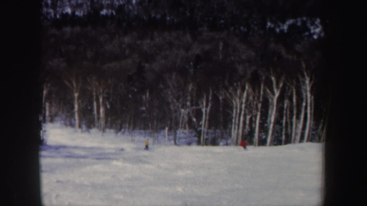 Final 1962 New Hampshire ski frame with red and yellow skiers spaced across a snowy wooded hillside.