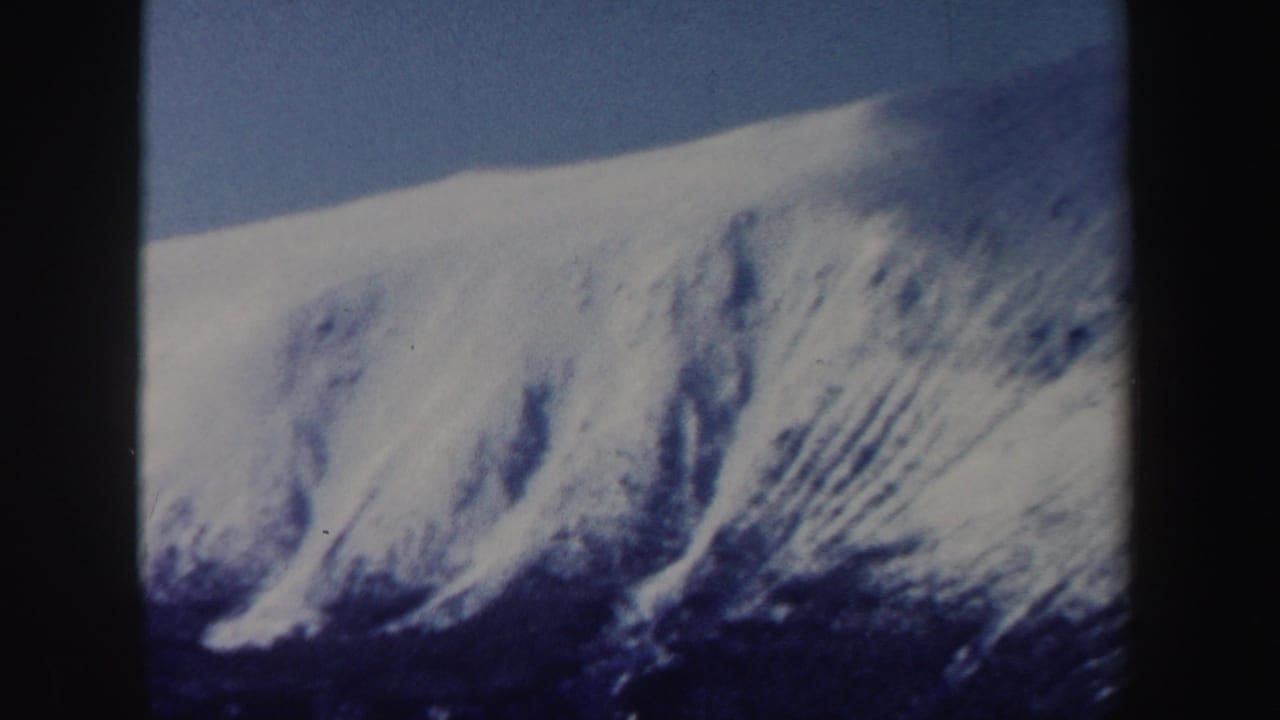Close 8mm home-movie view of a New Hampshire snow-covered mountain face during a strong zoom.