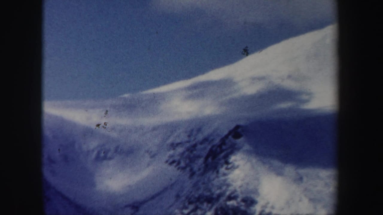 1962 New Hampshire 8mm frame showing a distant skier on a snow-covered slope beneath a bright sky.