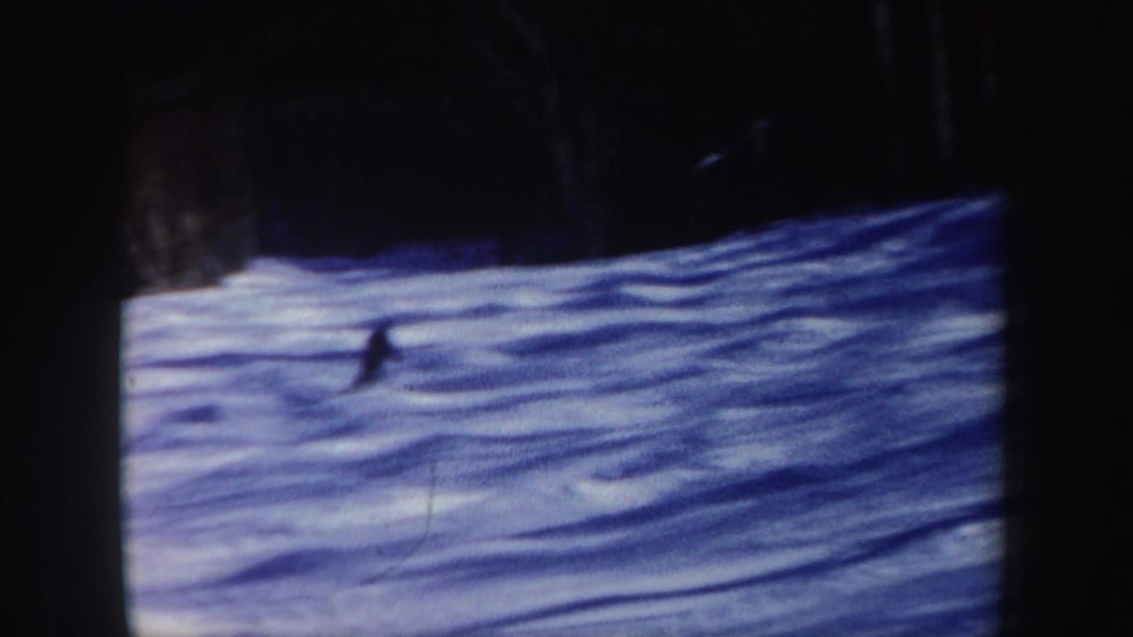 A lone skier descends a blue-tinted snowy slope in 1962 New Hampshire home-movie footage.