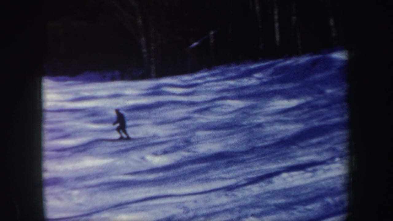 1962 New Hampshire home-movie frame of a lone skier gliding across a shadowed snowy slope.