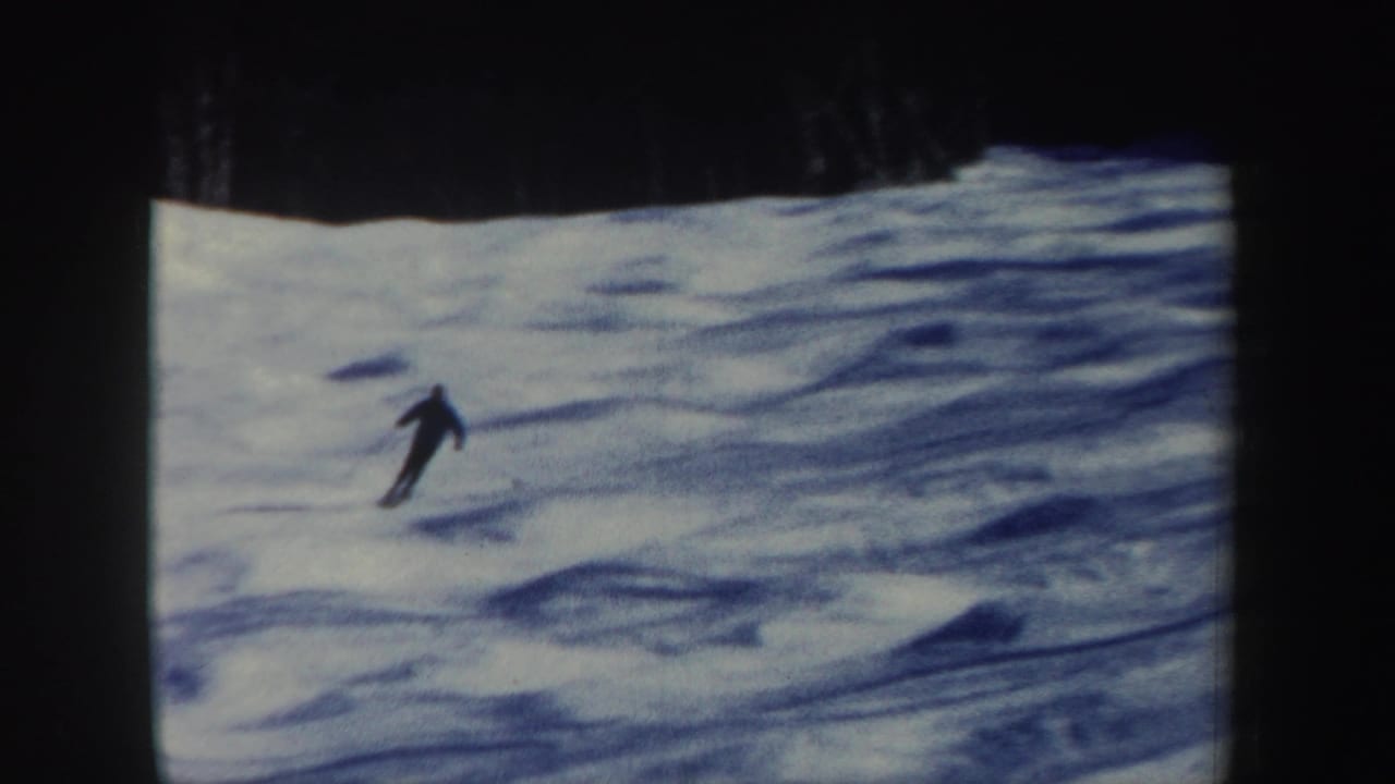 A lone skier descends an open snow-covered slope, seen from a distance in vintage 8mm footage from New Hampshire.