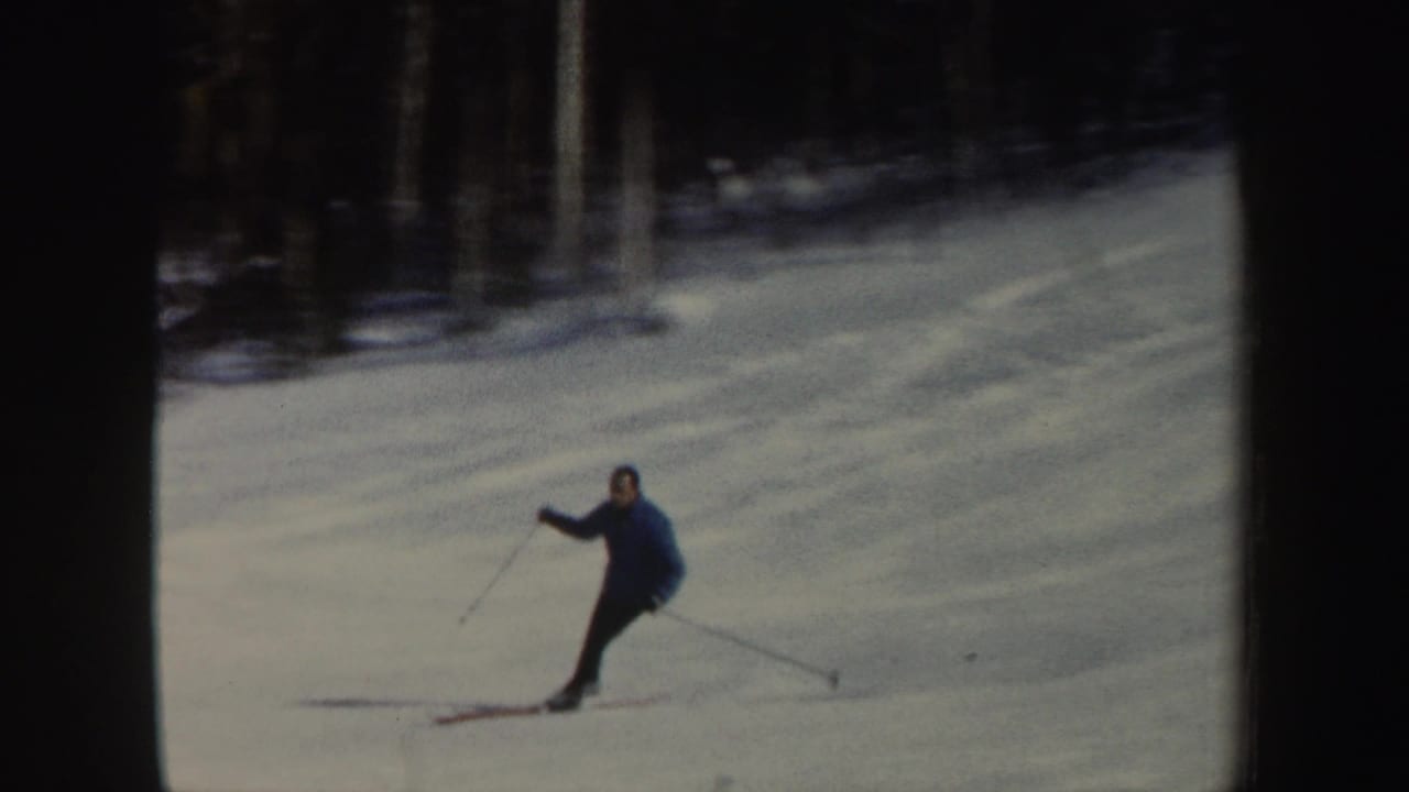 A closer 1962 home-movie frame shows the skier with poles extended, dark clothing, and blue-tinted snow across the slope.
