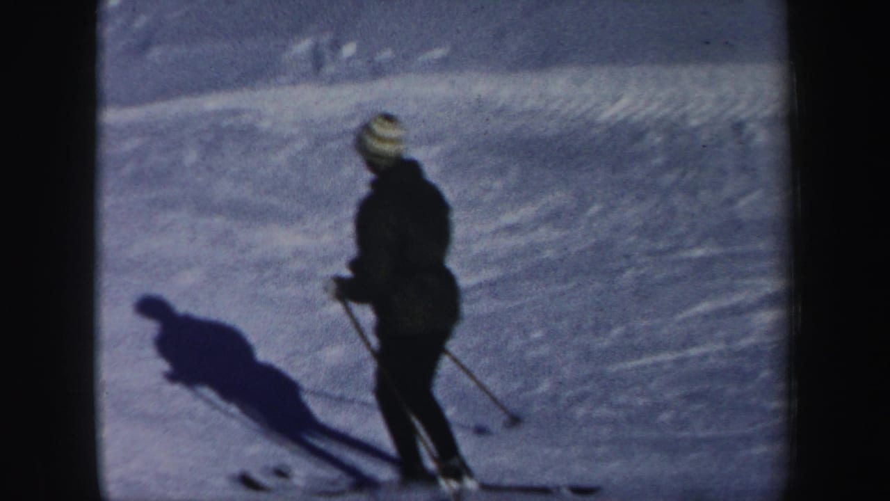 A lone skier in dark winter clothing and a striped knit hat appears on a New Hampshire snowy slope in 1962 footage.