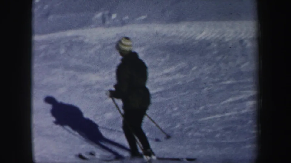A lone skier in dark winter clothing and a striped knit hat appears on a New Hampshire snowy slope in 1962 footage.