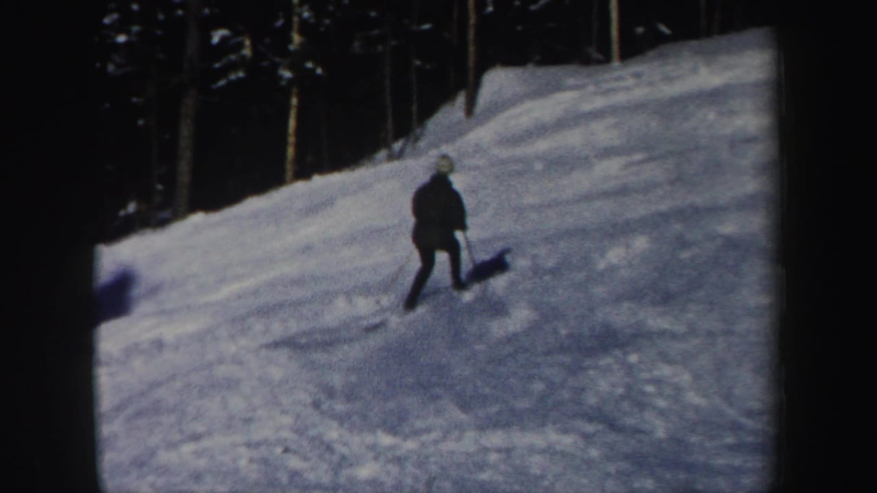 A skier continues across a snowy New Hampshire run near a line of trees in this 1962 home-movie frame.