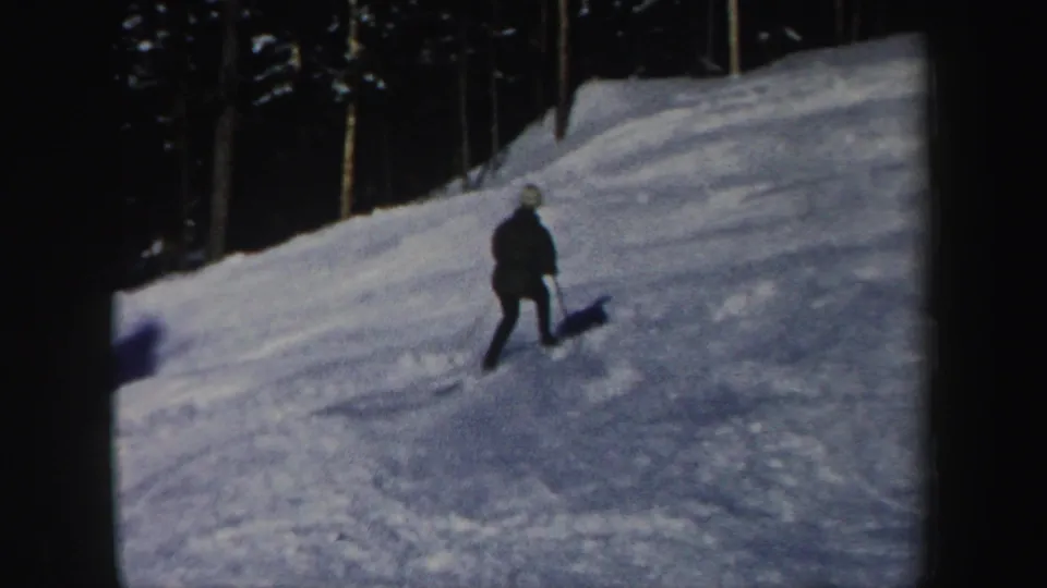 A skier continues across a snowy New Hampshire run near a line of trees in this 1962 home-movie frame.