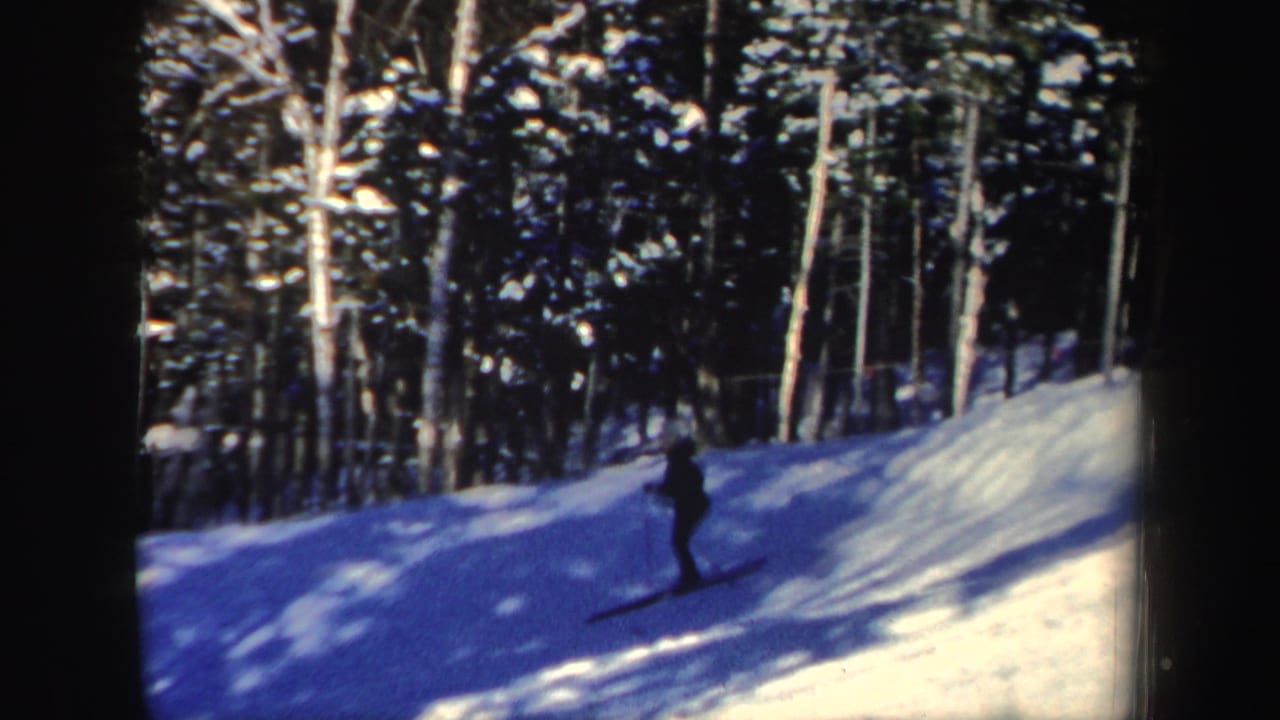 A small dark figure skis through the lower part of a snowy wooded New Hampshire slope.
