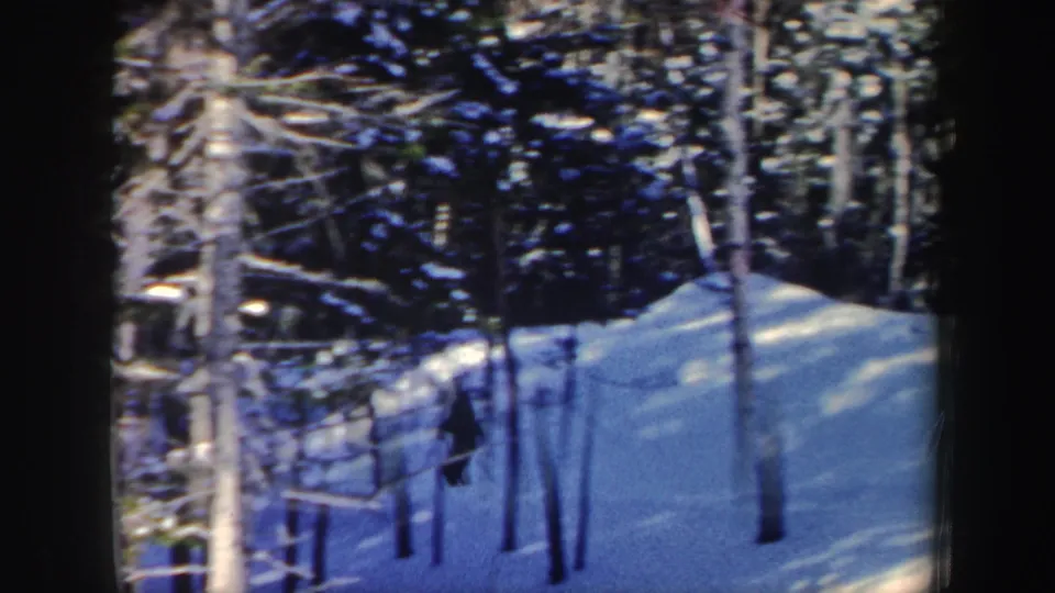 A distant skier crosses a snow-covered wooded slope in New Hampshire in this 1962 8mm home-movie frame.