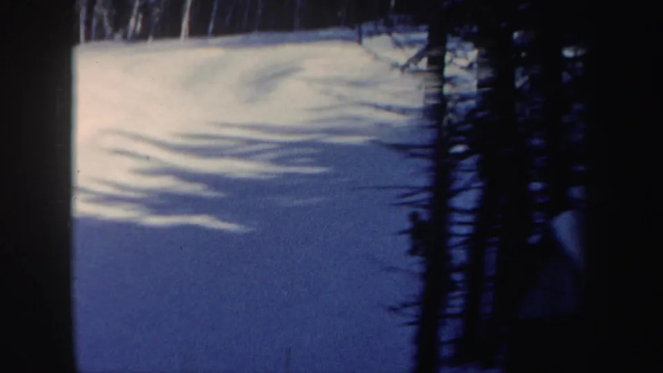 1962 New Hampshire 8mm view across an open snowfield with trees casting long shadows.