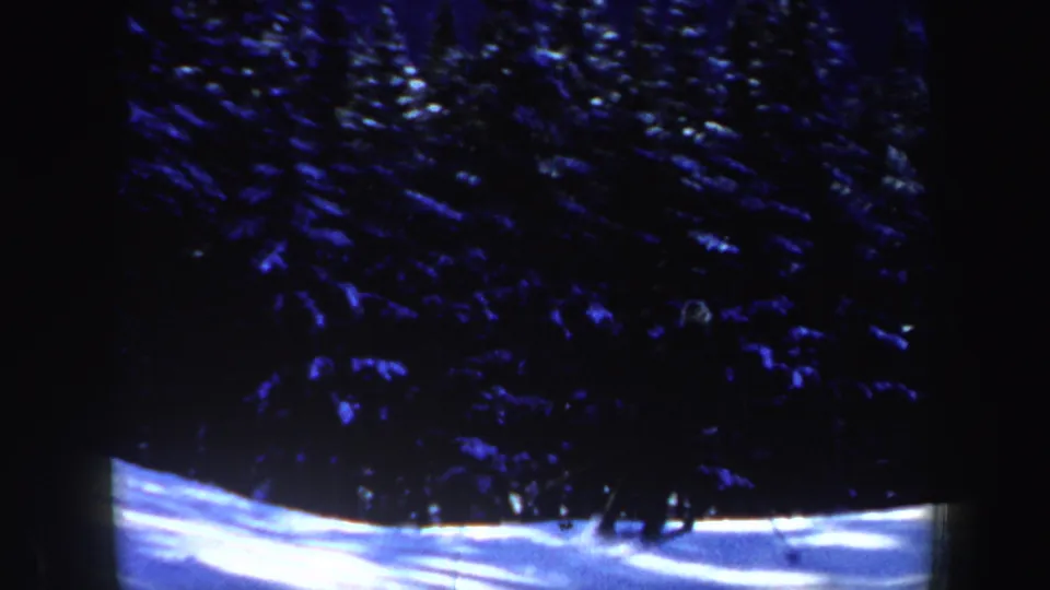 1962 New Hampshire 8mm frame showing a snow-covered slope beneath dense, shadowed evergreen trees.