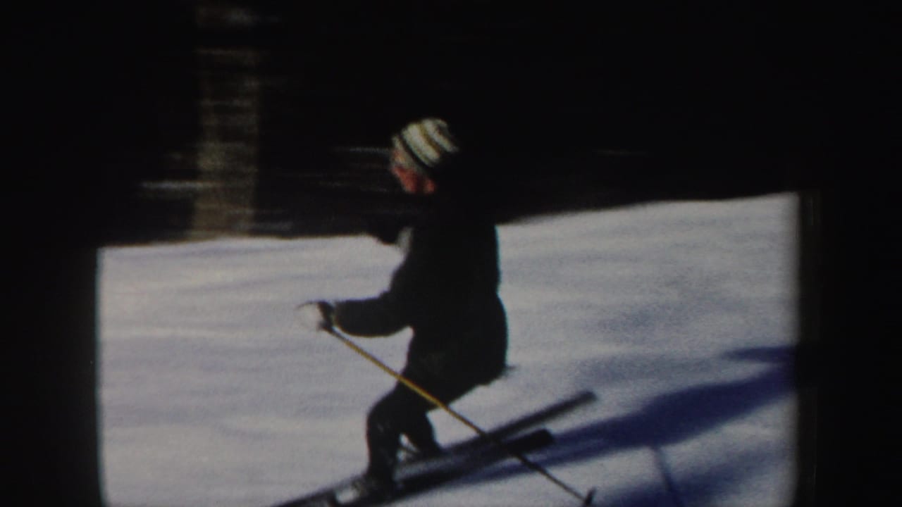 A skier wearing a striped knit cap passes across a snowy slope in 1962 New Hampshire home-movie footage.
