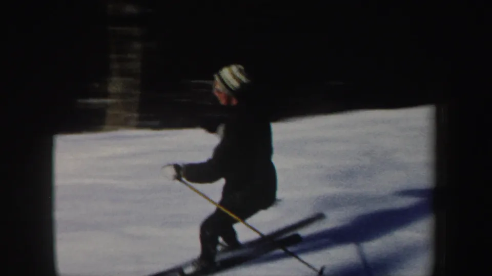 A skier wearing a striped knit cap passes across a snowy slope in 1962 New Hampshire home-movie footage.