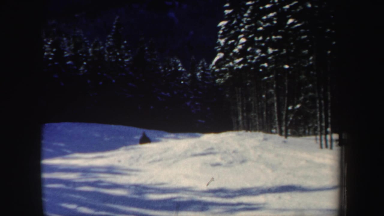 A 1962 New Hampshire ski-slope view shows snowbanks, evergreen trees, and a small skier near the upper slope.