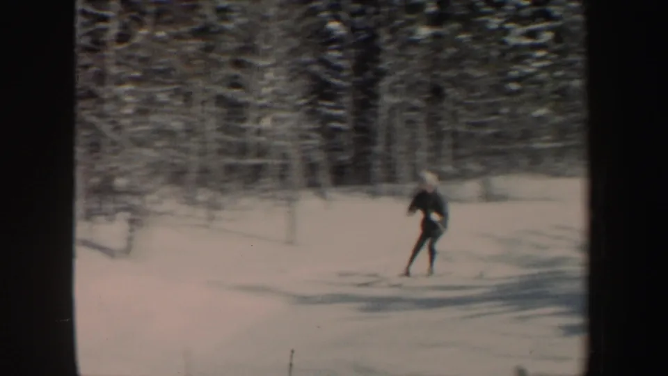 A closer frame shows the skier in dark winter clothing moving across snow with wooded terrain behind.