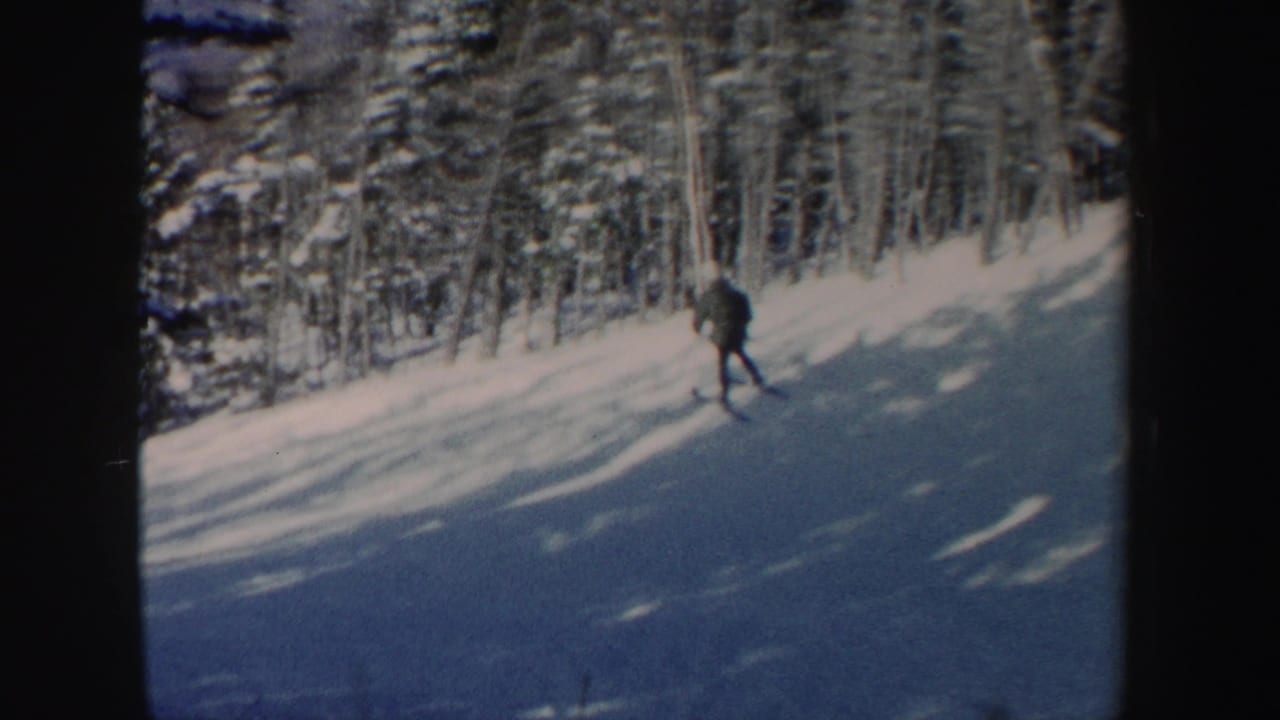 A skier moves downhill through a snowy New Hampshire forest setting in early-1960s 8mm footage.