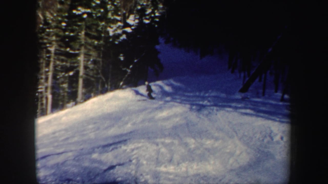 Near the end of the clip, the skier is distant on the New Hampshire slope, leaning slightly as the wooded trail curves through shadow.