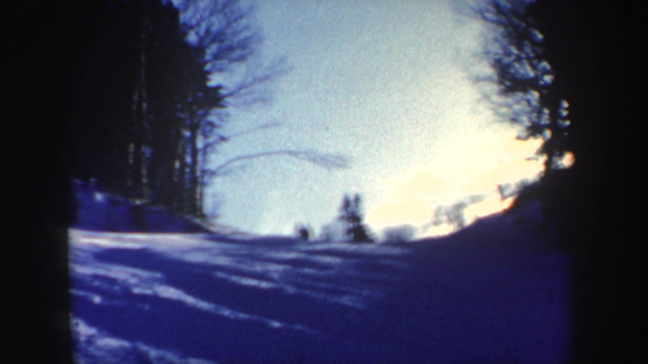 1962 New Hampshire winter footage shows a blue-toned snowy incline with distant skier-like silhouettes near the crest.