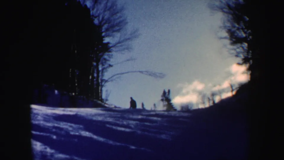 The final frame shows a distant person on a snow-covered New Hampshire slope, bordered by leafless trees in blue 8mm color.