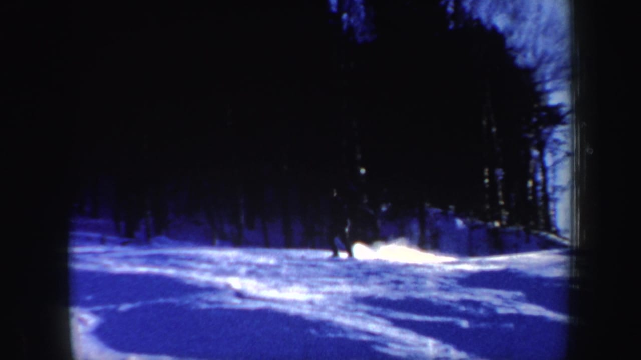 1962 New Hampshire winter frame with blue-toned snow and dense trees along a ski slope.
