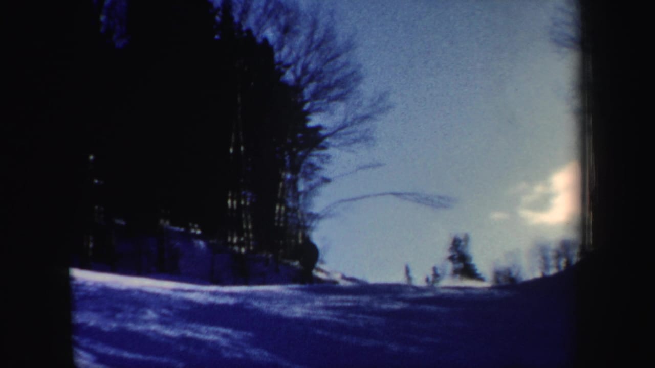 A skier approaches the lower slope in 1962 New Hampshire footage, seen against snow, bare trees, and blue winter light.