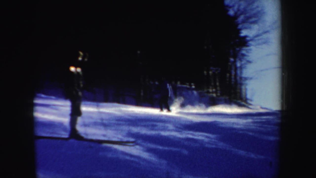 1962 New Hampshire ski-slope frame with one skier standing in shadow and another figure farther back on the snow.